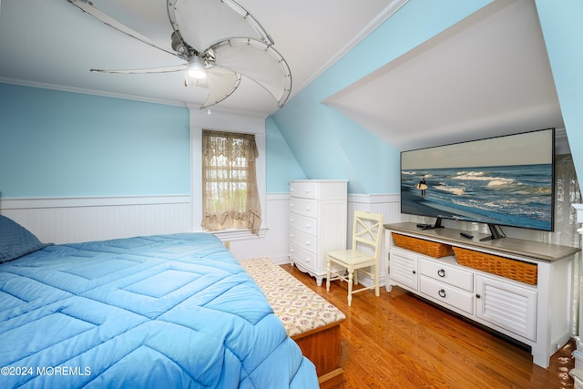 bedroom with ornamental molding, wainscoting, light wood finished floors, and a ceiling fan