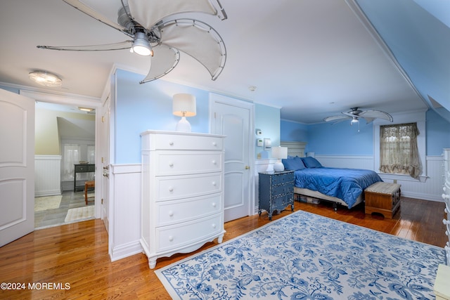 bedroom with a wainscoted wall, ceiling fan, wood finished floors, and crown molding