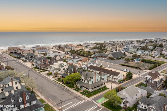 aerial view at dusk with a water view and a residential view