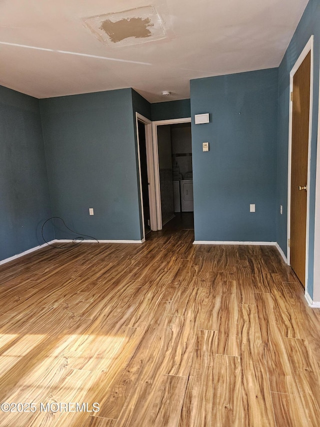 empty room with washing machine and dryer, baseboards, and wood finished floors