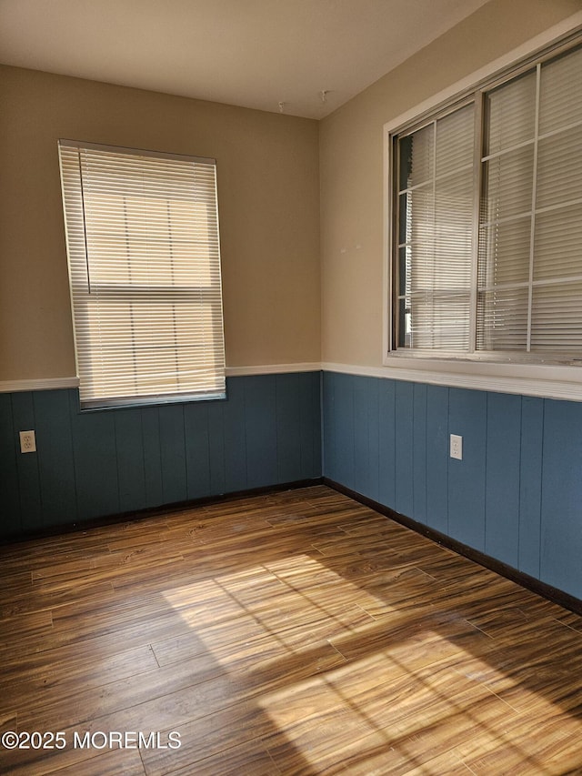 empty room featuring light wood finished floors and wainscoting