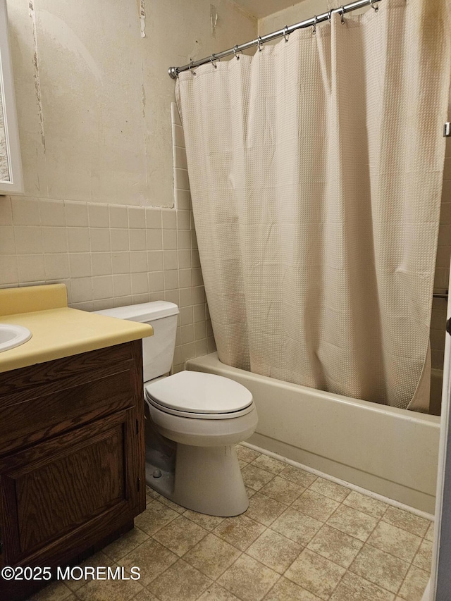 bathroom with shower / tub combo with curtain, vanity, toilet, and tile walls