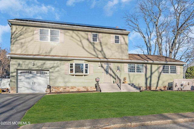 view of front of house featuring a front yard, roof mounted solar panels, entry steps, a garage, and driveway