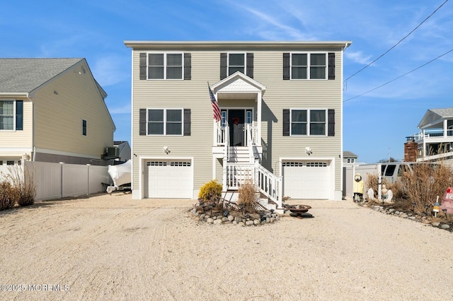 beach home with driveway, an attached garage, and fence