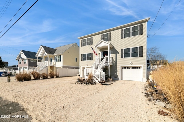 view of front of house featuring a garage, fence, stairs, driveway, and a residential view