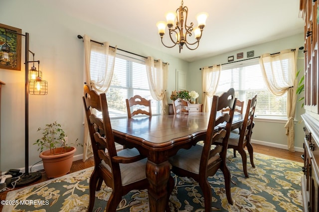 dining area with baseboards, wood finished floors, a wealth of natural light, and an inviting chandelier