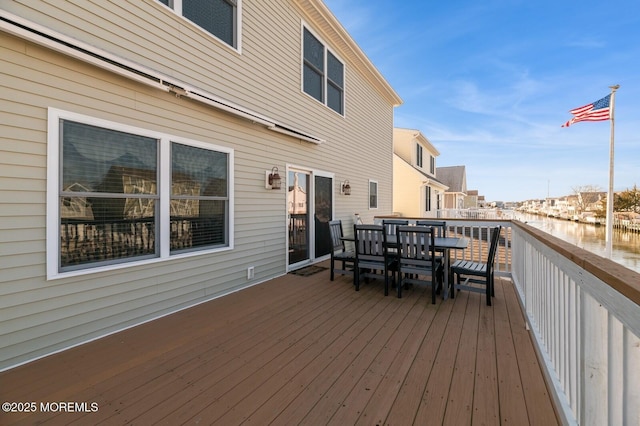 wooden deck with outdoor dining area and a water view