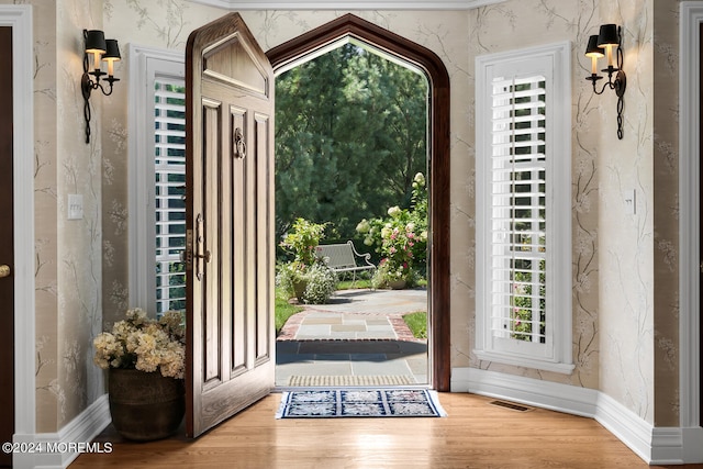 entryway with wallpapered walls, wood finished floors, visible vents, and baseboards