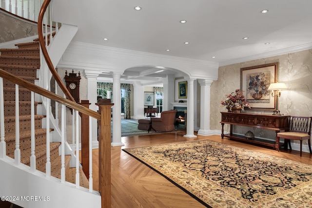 foyer featuring decorative columns, a lit fireplace, crown molding, and recessed lighting