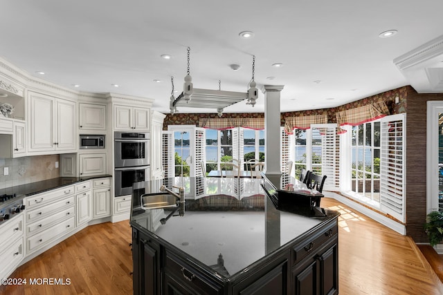 kitchen featuring stainless steel appliances, dark cabinetry, a kitchen island, and white cabinetry