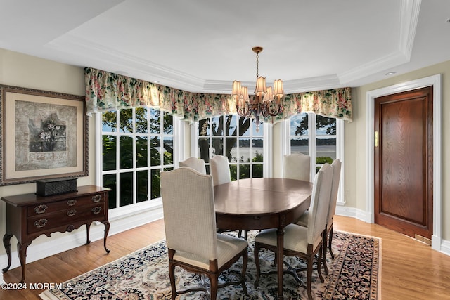 dining space with a chandelier, a tray ceiling, light wood finished floors, and baseboards