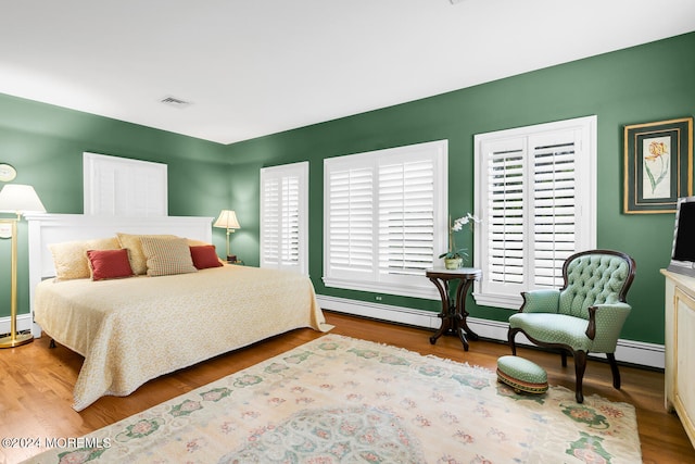 bedroom with baseboards, visible vents, and wood finished floors