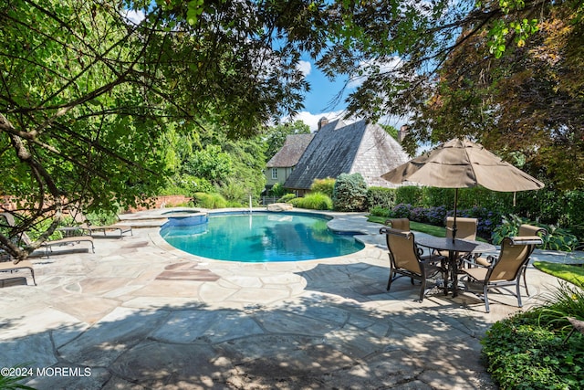 view of pool featuring a pool with connected hot tub and a patio