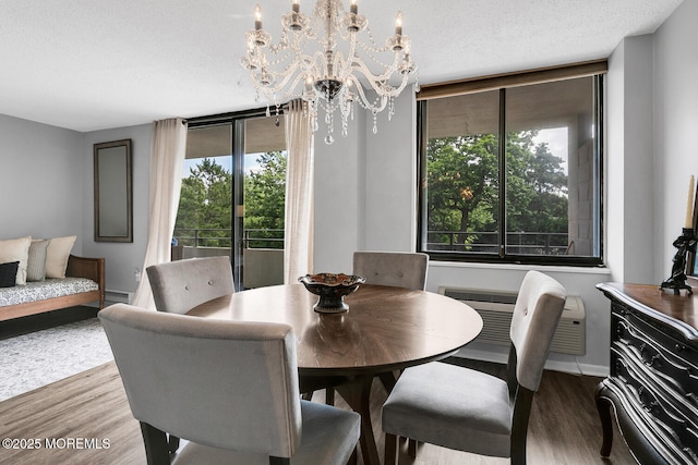 dining space with a chandelier, a textured ceiling, baseboards, and wood finished floors