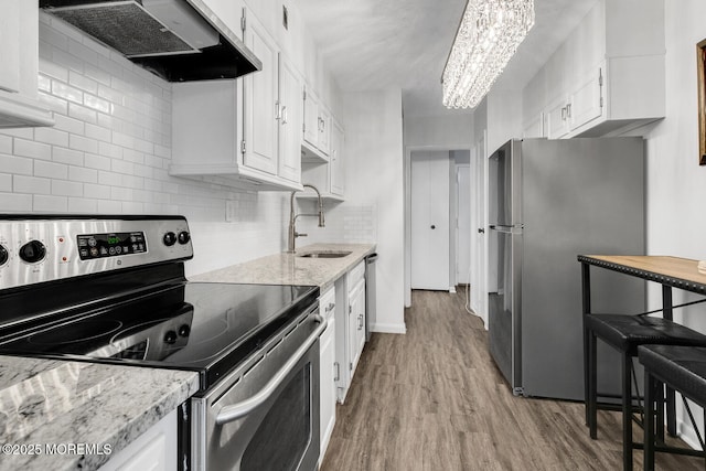 kitchen featuring appliances with stainless steel finishes, a sink, white cabinetry, and range hood