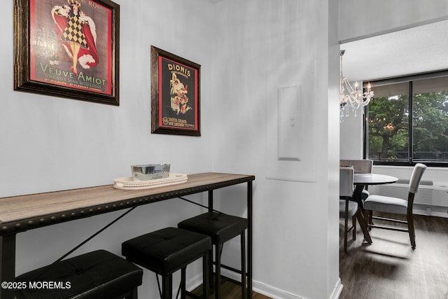 dining area featuring dark wood-style flooring, electric panel, an AC wall unit, and an inviting chandelier