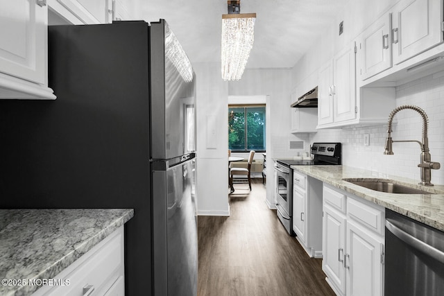 kitchen with dark wood finished floors, appliances with stainless steel finishes, white cabinetry, a sink, and light stone countertops