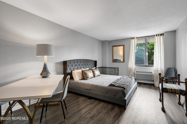 bedroom featuring a textured ceiling, dark wood-type flooring, and a wall unit AC