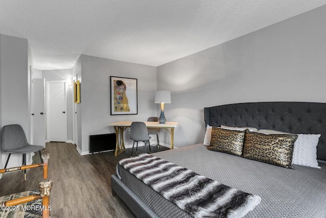 bedroom with a textured ceiling, dark wood-style flooring, and baseboards