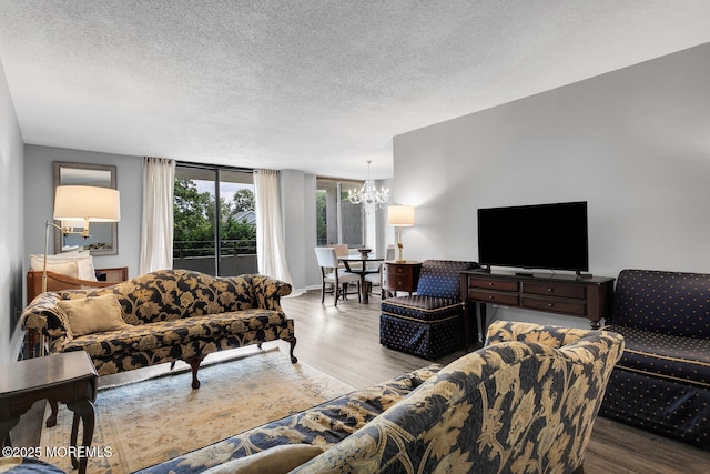 living area with an inviting chandelier, a textured ceiling, and wood finished floors