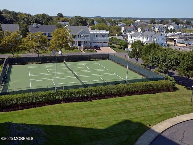 view of sport court with a residential view, fence, and a yard