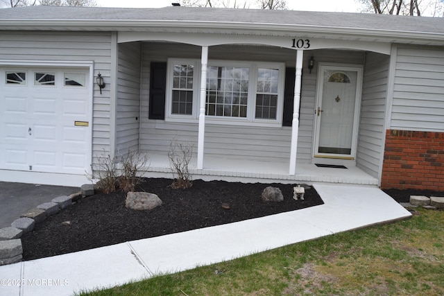 entrance to property featuring an attached garage, a shingled roof, and covered porch