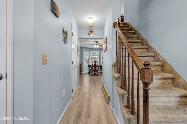 interior space with a baseboard radiator, baseboards, and wood finished floors