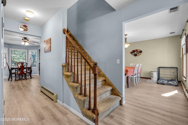 stairs featuring baseboards, visible vents, baseboard heating, and wood finished floors