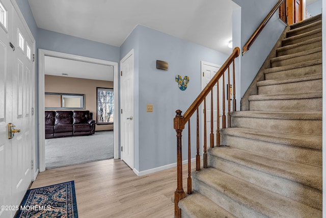 foyer entrance featuring light wood-style flooring, baseboards, and stairs