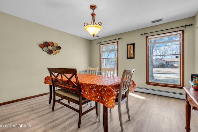 dining space featuring a baseboard heating unit, visible vents, light wood-style floors, and baseboards