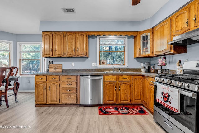 kitchen featuring dark countertops, under cabinet range hood, appliances with stainless steel finishes, and brown cabinets