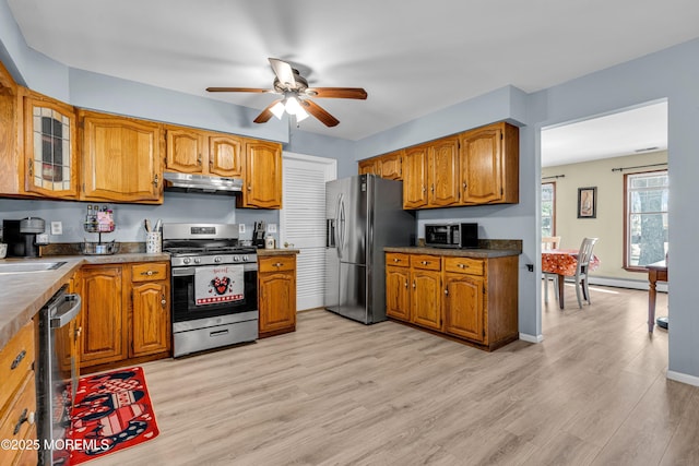 kitchen with dark countertops, under cabinet range hood, appliances with stainless steel finishes, and brown cabinets