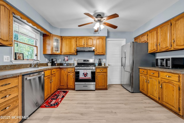 kitchen with under cabinet range hood, appliances with stainless steel finishes, light wood-style flooring, and brown cabinets