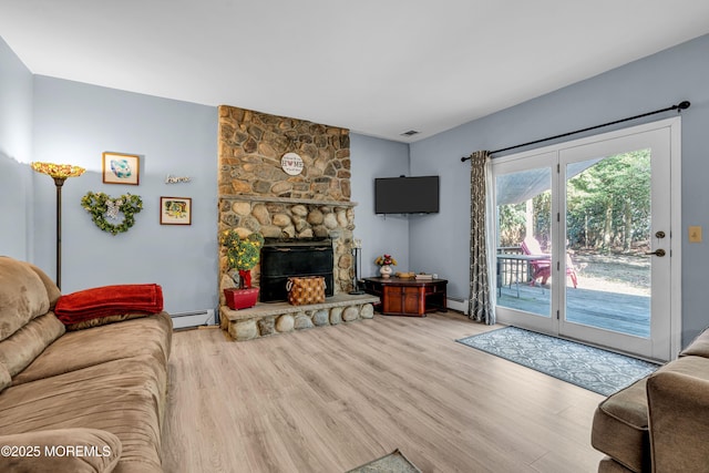 living area featuring a baseboard heating unit, a fireplace, and wood finished floors