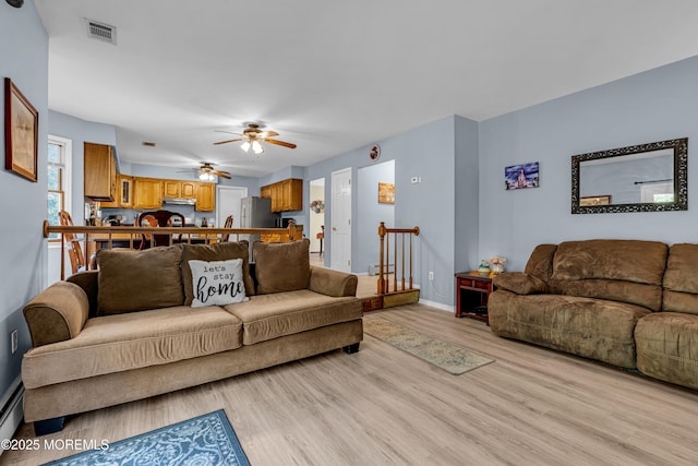 living room featuring visible vents, baseboards, a ceiling fan, a baseboard radiator, and light wood-style floors