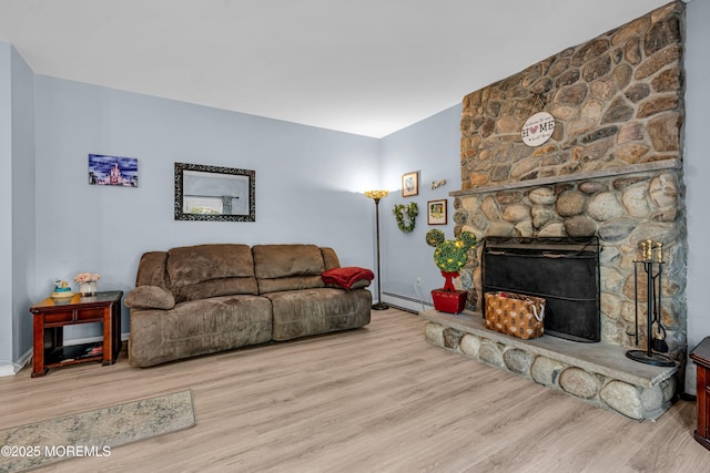 living area with a stone fireplace, light wood finished floors, and baseboard heating