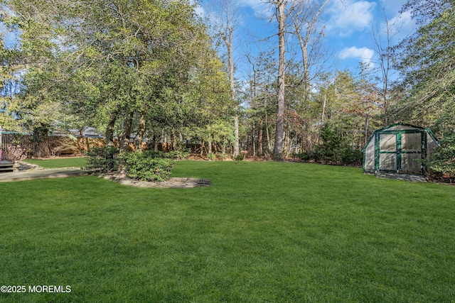 view of yard featuring an outbuilding, a shed, and fence