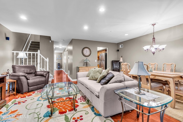 living room featuring a notable chandelier, light wood finished floors, recessed lighting, visible vents, and stairs