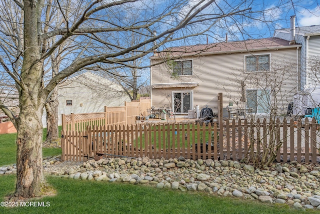 rear view of property featuring fence and a lawn