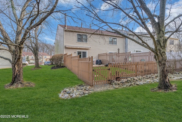 back of property with a lawn and fence