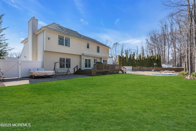 back of property with a deck, fence, a yard, a gate, and a fenced in pool