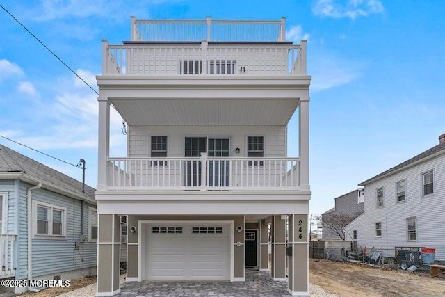 view of front of house featuring decorative driveway, a balcony, and an attached garage