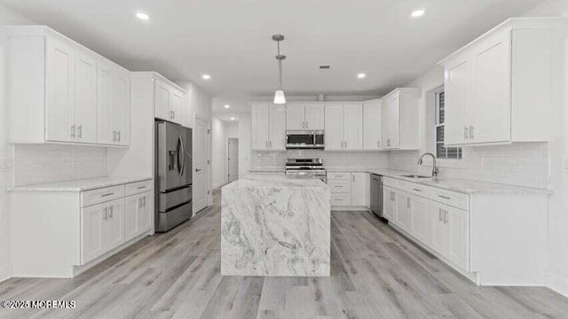 kitchen featuring light stone counters, a kitchen island, white cabinetry, hanging light fixtures, and appliances with stainless steel finishes