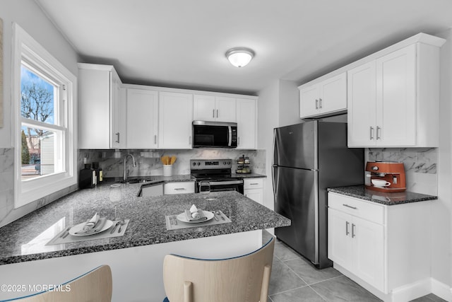 kitchen featuring stainless steel appliances, a peninsula, and white cabinetry