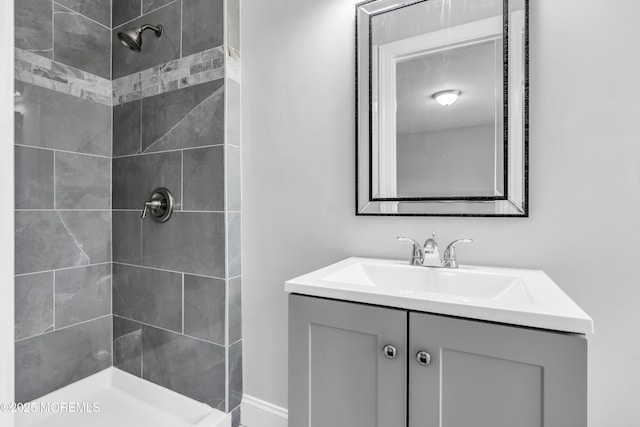 full bath featuring tiled shower and vanity