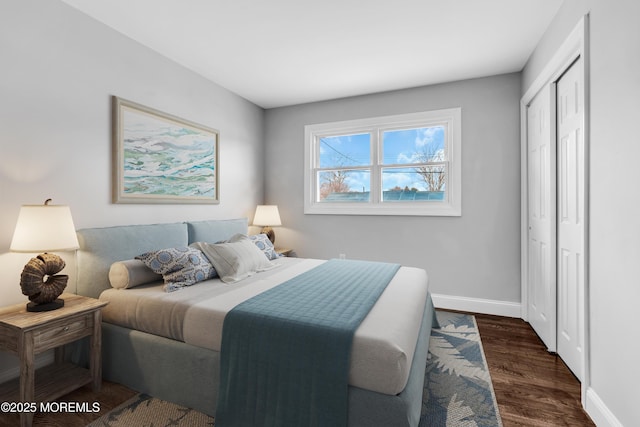 bedroom with a closet, dark wood-style flooring, and baseboards