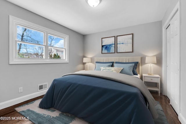 bedroom featuring dark wood-style floors, baseboards, visible vents, and a closet