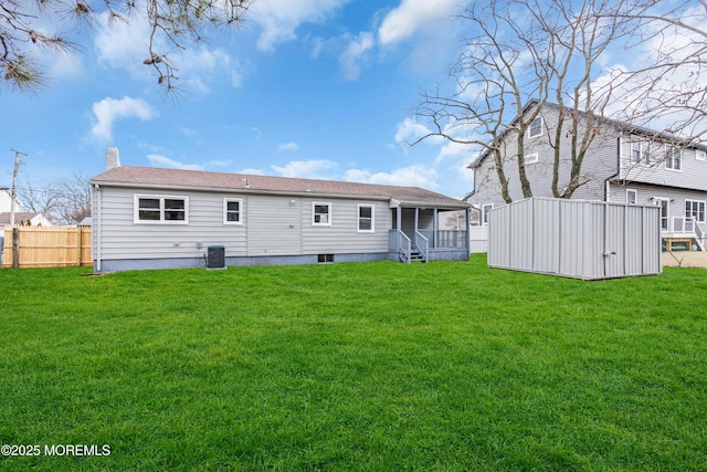 back of house with central AC, fence, and a lawn