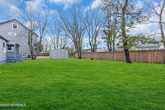 view of yard featuring a storage shed, an outdoor structure, and a fenced backyard