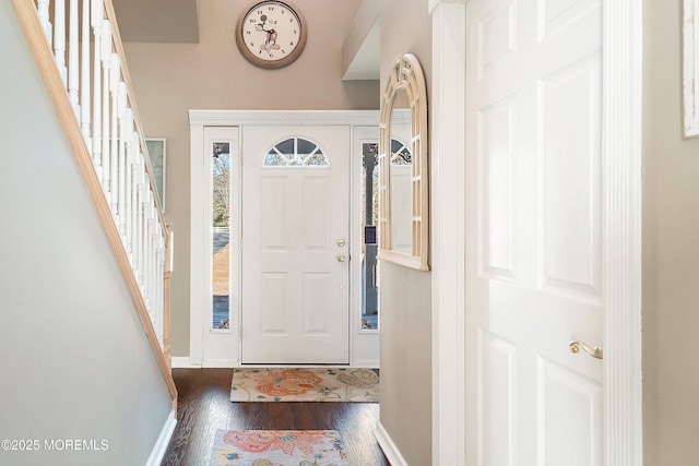 foyer entrance featuring dark wood-style floors, baseboards, and stairs